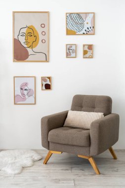 Çağdaş evdeki modern oturma odasının dikey fotoğrafı, tuğla duvarda sanat eserleri, minderli mobilyalar, rahat koltuk ve yerde kürk.