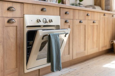 Açık kapılı gaz fırınına odaklan. Modern iç mekandaki ahşap mutfağın yan görünüşü, modern mobilyalar ve cihazlar üzerine inşa edilmiş vintage.