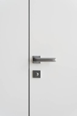 Kapalı kapı ve uzay duvarının minimalist sapı altında kilitli olan çağdaş iç tasarımın dikey fotoğrafı