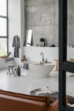 Beyaz banyo, seramik banyo, ev dekorasyonu ve gri beton duvara karşı havlular.