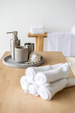 Sabun makinesine ve banyodaki ahşap raftaki dekorasyona özen göster. Güzellik ürünlerinin yakınındaki kaplıca salonundaki temiz ve taze havluların dikey fotoğrafı.
