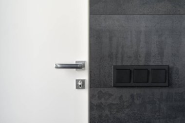 Modern iç tasarım elementi. Siyah fotokopi duvarında elektrik düğmesi var. Minimalist kapı kolunun yanında.