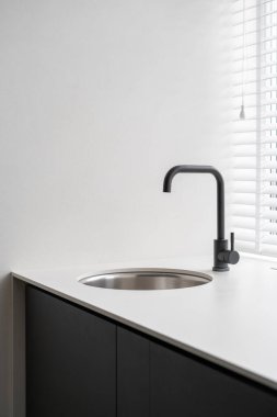 Yeni iç tasarımı, lavabosu ve su musluğu olan modern mutfak odasının dikey fotoğrafı, beyaz fotokopi duvarına karşı.