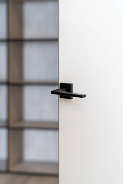 Arka planda bulanık bir oda olan açık kapının minimalist sapının dikey fotoğrafı. Kopya alanı ile çağdaş iç tasarım elementi