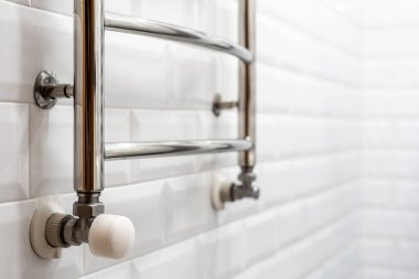 Metalik elektrikli havluya odaklan. Fotokopi arkaplanındaki fayanslı duvara yaslan. Modern dairede yeni banyo kavramı