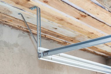 Ev yapım aşamasında. Yeni binadaki yeni garaj kapısı sistemi için ahşap tavanda metal korkuluk. Kopya uzay duvarına karşı.