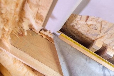 Ev yapım aşamasında. Modern modül binasının yeni pencere çerçevesi yakınındaki ahşap zemine karşı sarı mezura görüntüsünü kapat