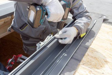 Profesyonel işçiyi elektrikli matkapla görmek, ahşap çatıdaki Mansard odasının pencere çerçevesini tamir etmek. Ev geliştirme ve inşaat konsepti