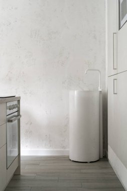 Mobilyaları, dolapları, beyaz beton lavabosu olan modern mutfak odasının dikey fotoğrafı, yeni iç tasarımda beyaz fotokopi duvarına karşı su musluğu