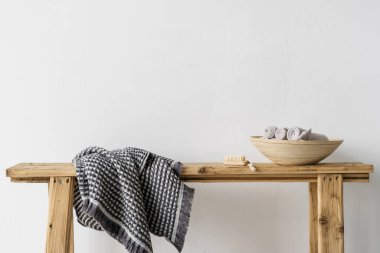 Banyo veya kaplıca salonunda beyaz fotokopi alanına karşı güzellik öğesi. Taze katlanmış havlular ahşap kasede yumuşak tırnak fırçasının ve temiz kumaşın yanındaki bankta yatıyor.