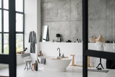 Modern banyo, modern iç tasarım, beyaz seramik küvet, ev dekorasyonu, temiz havlular, gri kopya alanı ve beton duvara karşı.