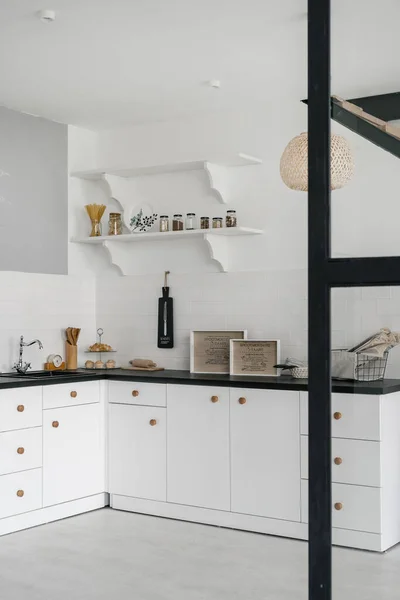 キャビネット シンク 水道管 部屋のタイル張りの壁に対する黒いカウンターの上の道具を引出しと白の近代的なキッチンの垂直面と側面の写真 — ストック写真