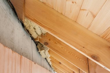 İnşaat geliştirme kavramı. Yeni ev inşaatındaki ahşap çatı kirişlerinin elementlerini kaya yünü termal yalıtım malzemesiyle kapatın.