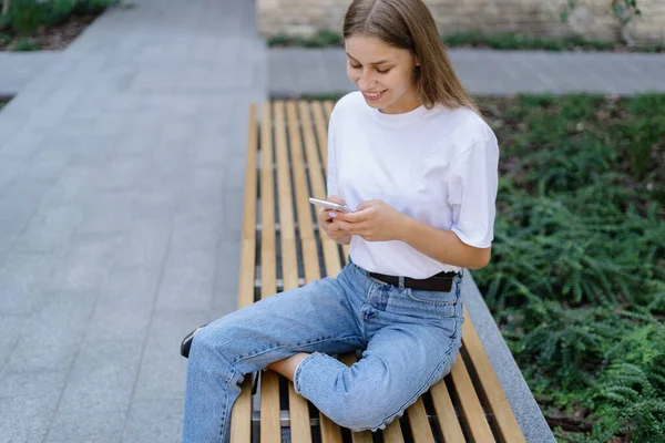 Modern akıllı telefonda online uygulama kullanan, mesajlaşan, blog okuyan ve sosyal uzaklıktaki arkadaşlarıyla iletişim kuran mutlu akademi öğrencisinin yüksek açılı görüntüsü