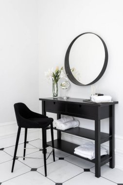 Modern evdeki modern iç tasarımın dikey fotoğrafı makyaj masası, rahat koltuğu, temiz havlular, doğal makyaj malzemesi ve aroma sahnesi. Sabah rutini kavramı