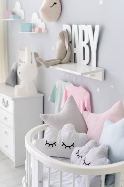 Beşik yatağında yastıkları olan yeni doğan çocuklar için dikey yatak odası, beyaz ahşap tuvalet, oyuncaklar ve ev dekorasyonu İskandinav iç tasarımı ile bulanık arka plan