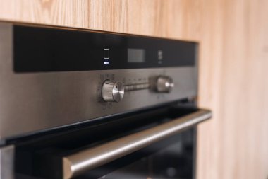 Modern siyah fırında sezgisel kadranlar ve modern bir mutfağın şık ahşap içiyle mükemmel bir şekilde harmanlanmış, işlevselliğini ve tasarımını geliştiren dijital bir ekran bulunur..