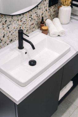 Çağdaş bir banyoda parlak bir lavabo, modern iç uzayda sükunet hissi uyandıran minimalist bir musluğu temsil eder. Otel odasındaki beyaz seramik lavabonun yüksek açılı görüntüsü