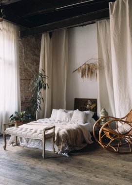 Bu şık yatak odası, keten ve battaniyelerle süslenmiş rahat bir yatak, şık bir sallanan sandalye ve yeşillik içeriyor. Rahatlamak için sıcak ve davetkar bir atmosfer yaratıyor..