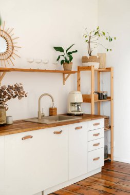 Parlak mutfak, doğal dekorasyonu, ahşap rafı ve lavabosu olan modern tezgahı olan bohem tarzı bir iç mekan sergiliyor. Eski tarz kahve makinesi, dikey çekim.
