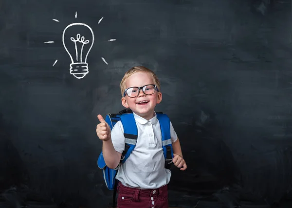 回学校去小学快乐的孩子 黑板上挂着灯泡 戴眼镜的孩子真有趣 天才小子带着灯泡成功 双赢和创新的技术概念 — 图库照片