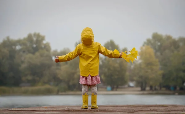 Happy girl in yellow raincoat and boots