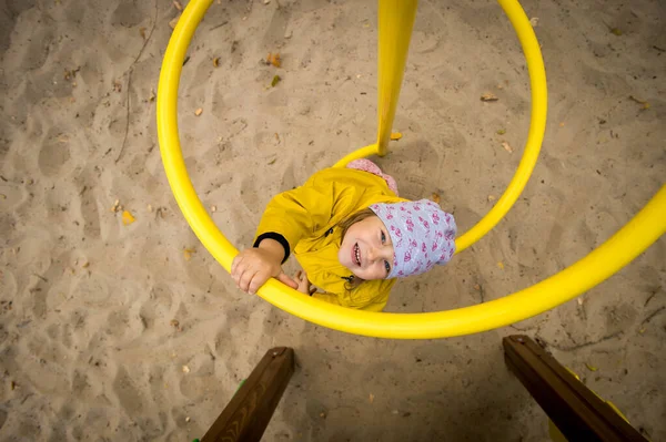 Szczęśliwa Dziewczynka Żółtym Płaszczu Bawiąca Się Zewnątrz Placu Zabaw Słoneczny — Zdjęcie stockowe