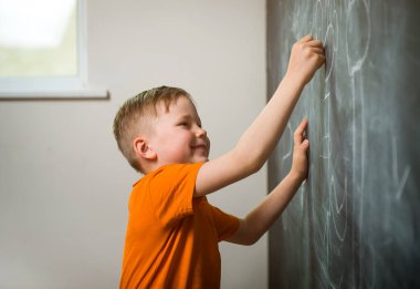 Küçük çocuk tahtaya yazı yazıyor. Mutlu çocuk say ve numara çek. Okula geri dön..