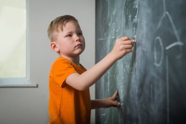 Küçük çocuk tahtaya yazı yazıyor. Mutlu çocuk say ve numara çek. Okula geri dön..