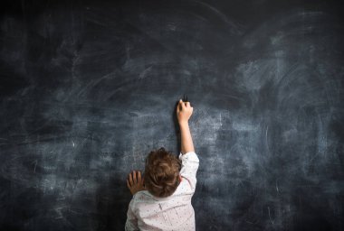 Okula dönelim. Tahtaya karşı duran çocuk. 