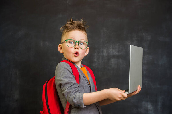 Child using a laptop computer with blackboard background.
