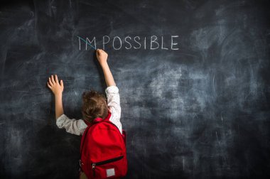 Sevimli küçük çocuk kara tahtaya haç koyuyor..