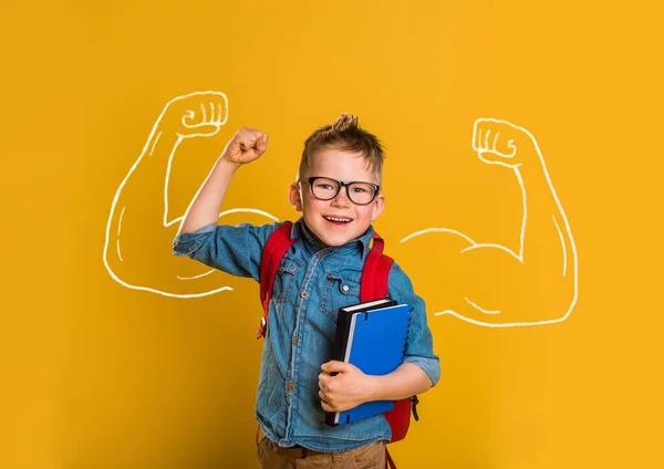 子供時代 強さと人々の概念 黄色の学校の壁の背景に強い拳を示す幸せな笑顔の少年 — ストック写真