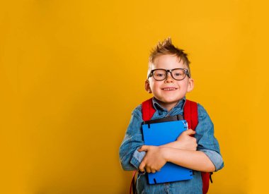 Mutlu çocuk sarı arka planda büyük bir kitabı tutuyor ya da sarılıyor. Okula geri dön..