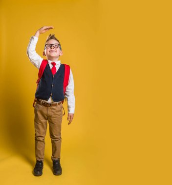 Etkilenmiş çocuğun boy boy boy fotoğrafı kol ölçülerini yükselt beklenmedik haberler aç ağız aç moda modaya uygun kıyafetleri pastel arka planda izole et. Okula geri dön..