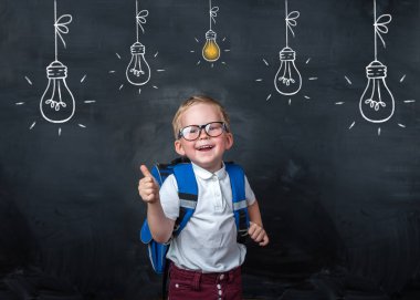 Okula dönelim. Gözlüklü komik çocuk tahtayı işaret ediyor. İlkokuldan elinde kitap ve çantayla bir çocuk. Eğitim. Tahtada ışık olan ampul.
