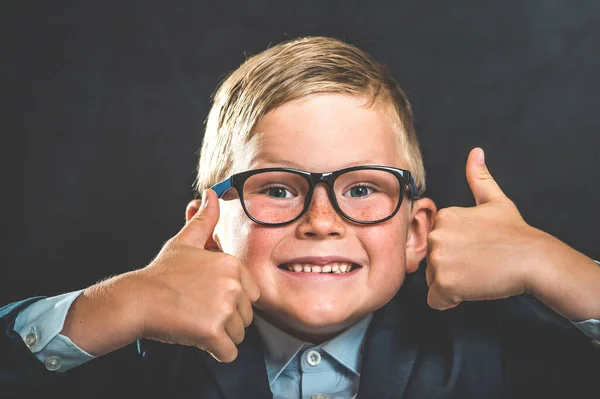 聪明学童的肖像 大拇指在黑板旁 空白处 看着相机 快乐的男孩穿制服 回学校去吧秋天的第一天 有趣的脸 — 图库照片