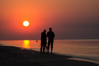 Yeni günü kucaklıyorum. Deniz kıyısındaki insanlar. Güneş doğuyor. Fotoğraf makinesinde resim yapmak. Fotoğrafçılar..