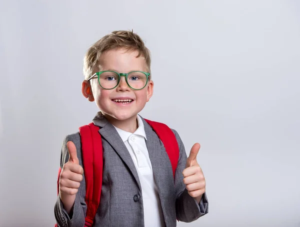快乐的小男孩 背着白色背景的背包 回学校去一个大拇指向上的快乐学生 戴眼镜笑着脸 — 图库照片