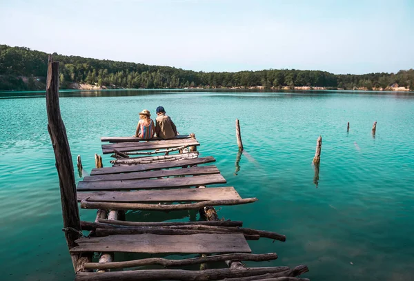 Przyjaciół dzieci siedzących na molo na pięknym jeziorze. Chłopiec i dziewczynka. Rozgląda się. Czysta niebieska woda. Samotne dzieci na dzikiej przyrodzie. Filtr Instagrama. — Zdjęcie stockowe