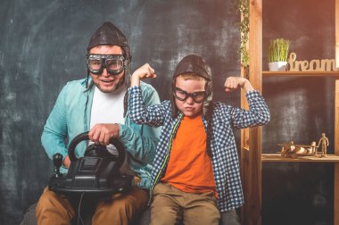 Video oyun kumandalı bir adam ve genç çocuk. Evde eğlenceli bir aile hobisi. Küçük okul çocuğu, mutlu bir babayla oynuyor. Heyecanlı iki erkek nesil ailesi video oyunundan zevk alıyor