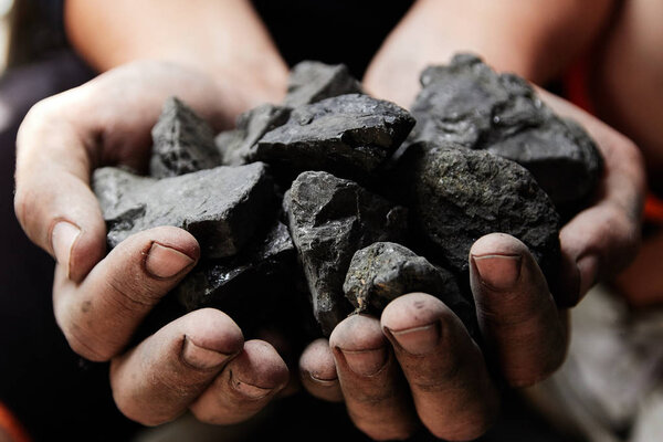 Coal miner in the man hands of coal background. Coal mining or energy source, environment protection. Industrial coals. Volcanic rock.