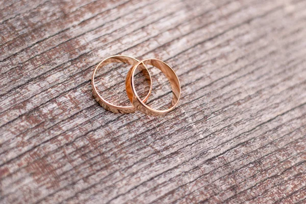 Two golden wedding rings on wood background