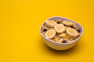 Muz, yulaf ve Mısır gevreği, sarı arka plan beyaz bir kase. Mükemmel beslenme sağlıklı beslenme veya kahvaltı.