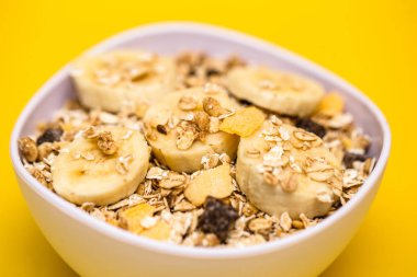 Muz, yulaf ve Mısır gevreği, sarı arka plan beyaz bir kase. Mükemmel beslenme sağlıklı beslenme veya kahvaltı.