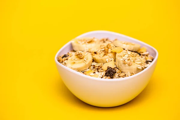 バナナ オートミール シリアル 黄色の背景の白いボウル 健康的なダイエットや朝食のための完璧な栄養 — ストック写真