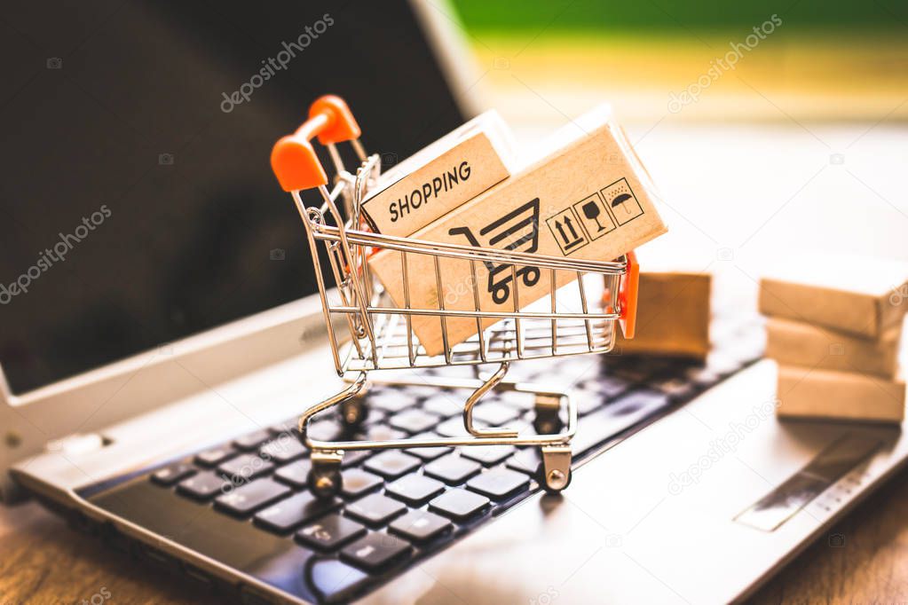 Boxes in a shopping cart over laptop keyboard.Concept about shopping and online sales. Buy your goods directly from the Internet, from the comfort of your home.