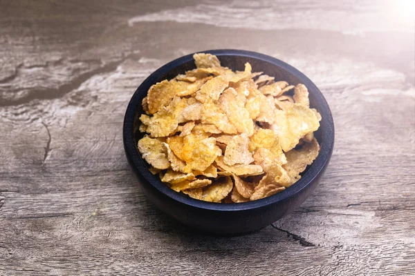 Corn flakes and bowl on wooden table Selective focus corn flakes in bowl