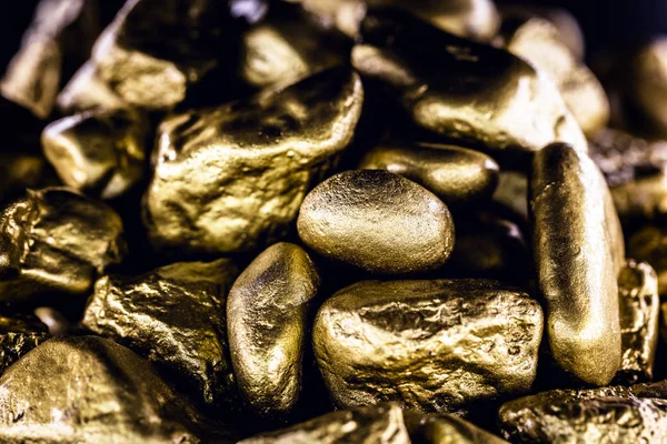 Gold nugget, large gold stone closeup isolated on black background. Concept of finance, luxury or wealth.