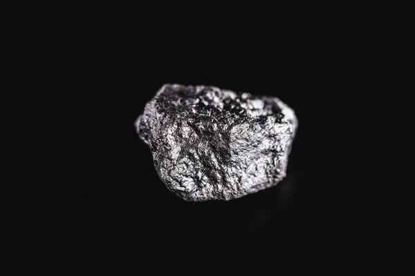 Grosse pépite argentée sur fond noir. Pierre d'argent brut, pépite d'argent originaire du Libéria, isolée sur fond noir. Extraction minérale . — Photo